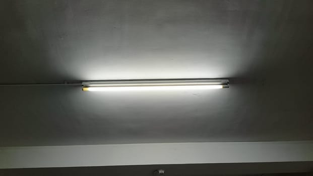 A simple fluorescent light provides illumination in a minimalist industrial space. The image captures a clean and modern ceiling with soft lighting effects.