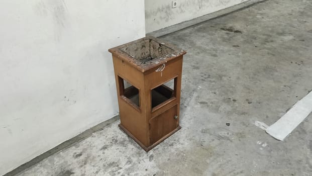 An old brown wooden drawer stands alone in a neglected concrete space, suggesting themes of abandonment and time. The industrial environment adds to the sense of decay and desolation.