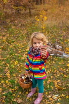 Child with a basket of mushrooms in the forest. Selective focus. nature.