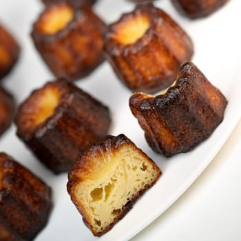 Caneles de bordeaux, traditional French sweet dessert with white table background, High quality photo