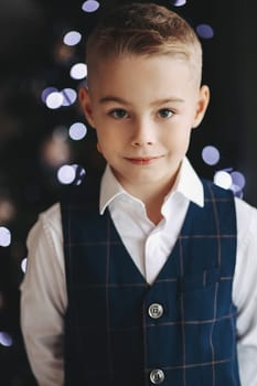 A handsome boy in a stylish outfit smiles, looks at the camera, poses.