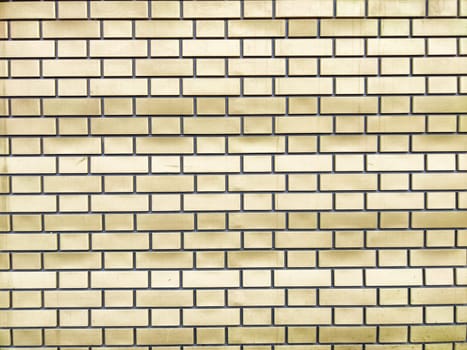 A close-up view of a yellow brick wall with a structured layout and even spacing between the bricks.