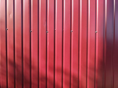 A vibrant red textured wall featuring vertical metal panels, creating a modern backdrop with ample copy space for branding.