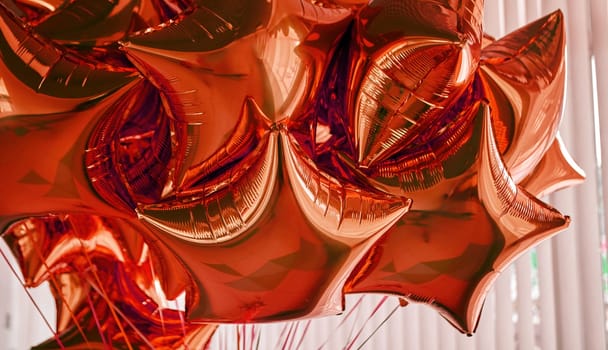 A cluster of reflective red star-shaped balloons is suspended in mid-air, contributing a cheerful atmosphere to a festive event or party setting.