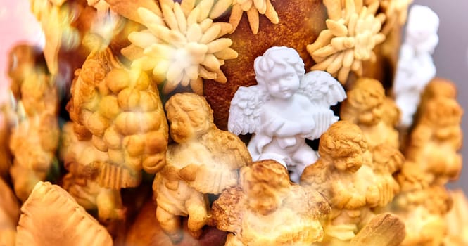 Christmas composition with a figurine of an angel made of sugar on a large pie, surrounded by angels made of dough, close-up. Focus on the foreground.