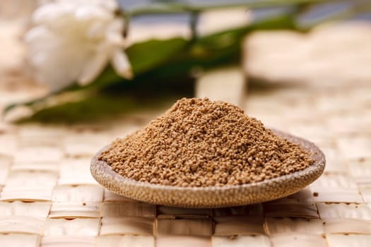 Raw Sucanat sugar displayed on a wooden spoon.