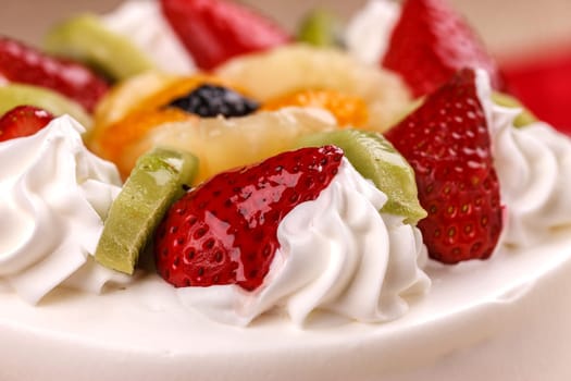 A close up of a white cake topped with various fruits.