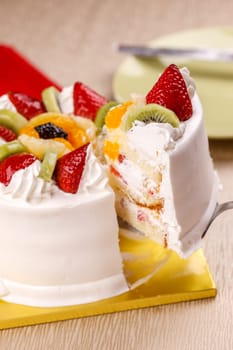 Lifting a slice of white cake topped with fresh fruit.