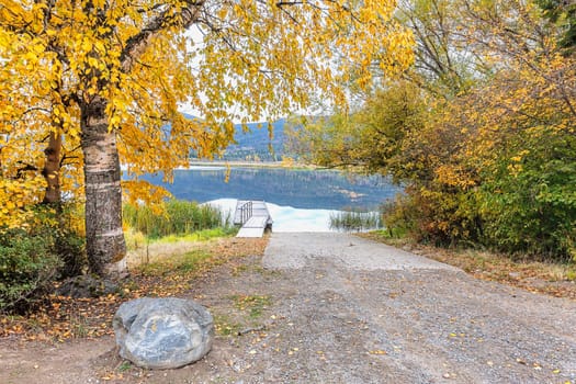 Trees with yellow leaves layer over the ramp to the dock on McArthur Lake in north Idaho.