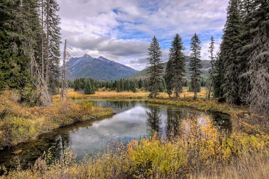The calm Mirror Pond under a partly cloudy sky along highway 56 in western Montana.