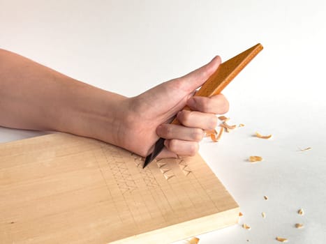 Hand engraving wood with chisel, artistic craftsmanship in action.