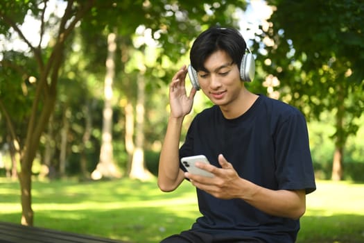 Smiling sportsman listening to music and using mobile phone after running.