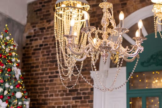 Cozy white Christmas interior room. Living room with Christmas tree, white sofa, crystal chandelier