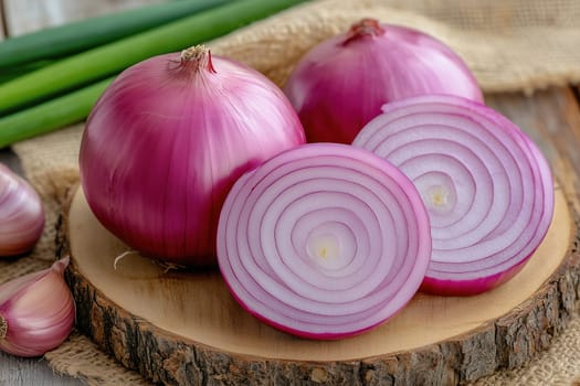 Red onions are arranged on a wooden cutting board, showcasing a sliced onion with concentric rings. Green scallions add color, highlighting fresh ingredients in a kitchen.