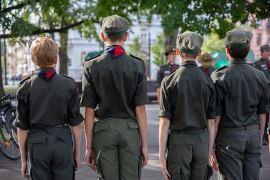A group of young cadets proudly standing in formation during a solemn outdoor ceremony in the warm sunshine