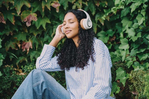 A young woman listens to her favorite music using headphones, fully immersed in enjoying a perfect moment of tranquility and peace in a stunning and beautiful natural setting that surrounds her