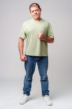 A middle-aged man stands confidently in casual attire against a neutral background close up