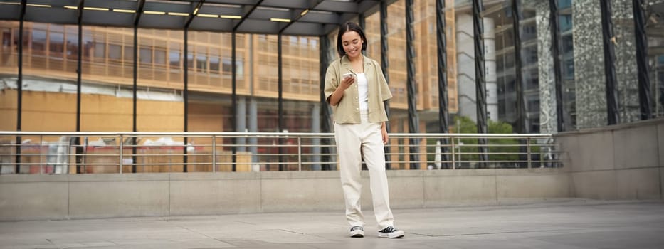 Portrait of asian female model with telephone. Young korean girl holding smartphone on street, using telephone.