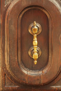 Fragment of an old wooden door with a metal handle.