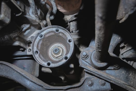 The driveshaft flange under the bottom of the car. Automotive background of transmission repair and driveshaft restoration.