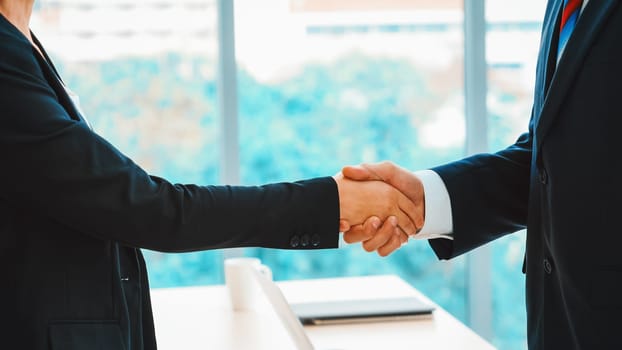 Business people handshake in corporate office showing professional agreement on a financial deal contract. Jivy