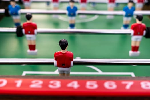 Table football. Close-up of figures of plastic players in a football match. red and blue players kick the ball.