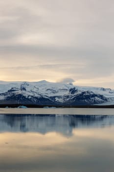 Ice covered hillsides and large scandinavian lake in arctic region of Iceland. Winter wonderland stunning route with incredible sundown light during golden hour, polar adventure.