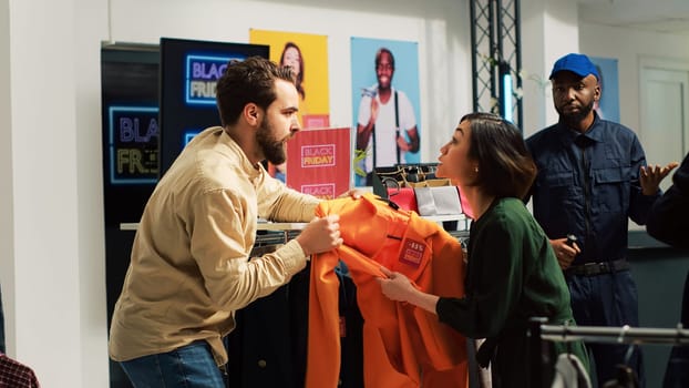 Black Friday fight in clothing store. Mad shoppers fighting over clothes during seasonal sales at mall, angry customers pulling clothing item and arguing, various brands on discount.