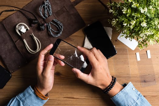 The man replacing the broken tempered glass screen protector for smartphone.