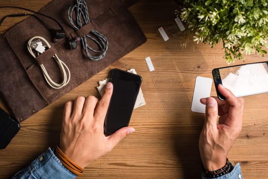 The man replacing the broken tempered glass screen protector for smartphone.