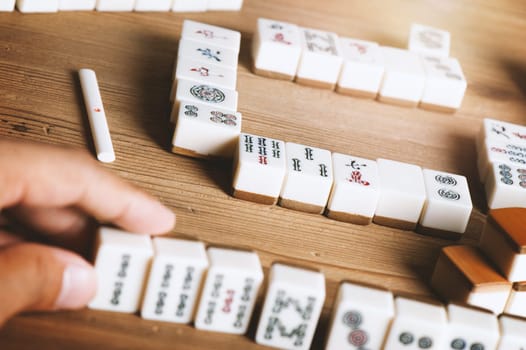 Playing Mahjong on wooden table. Mahjong is the ancient asian board game.