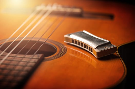 vintage wooden harmonica lying on an old acoustic guitar.