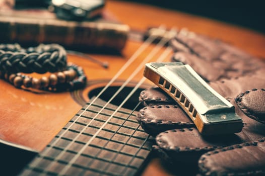 vintage wooden harmonica lying on an old acoustic guitar.