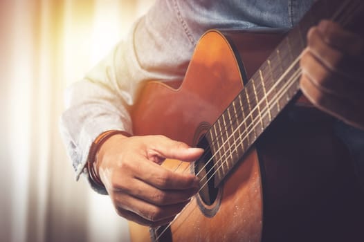 closeup man's hand playing his old classical guitar.