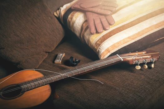 vintage classical guitar with breaked string on the sofa.