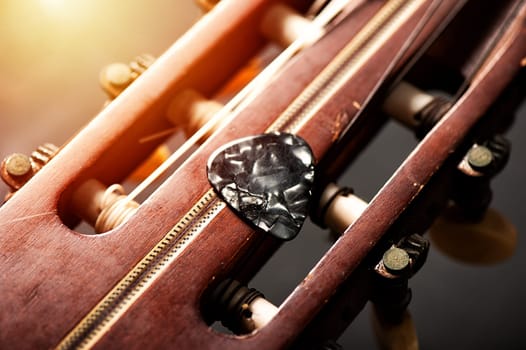 Closeup guitar pick on an old classical guitar. A guitar pick is a plectrum used for guitars.