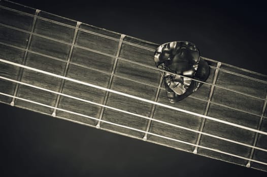 Closeup guitar pick on an old classical guitar. A guitar pick is a plectrum used for guitars.