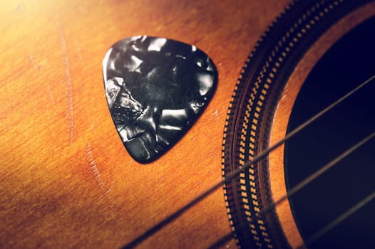 Closeup guitar pick on an old classical guitar. A guitar pick is a plectrum used for guitars.