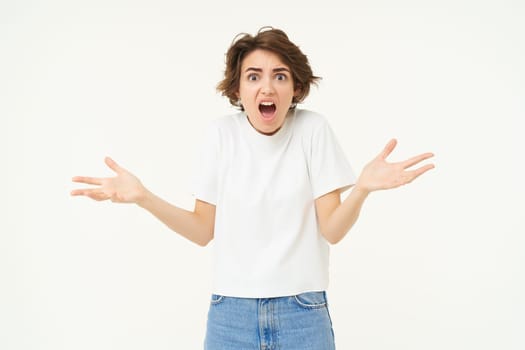 Frustrated young woman, looking upset and disappointed, complaining, screaming from distress and anger, standing over white studio background.