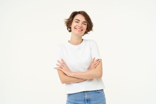 Portrait of cheerful woman laughing and smiling, cross arms on chest, standing in confident power pose, young professional concept, white studio background.