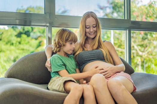 A heartwarming moment: pregnant mother and her older son sit on the sofa, engaging in a tender conversation about the upcoming pregnancy.