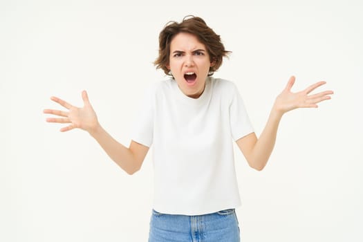 Portrait of woman throwing tantrum, shouting and screaming, shaking hands and yelling outraged, standing over white studio background.