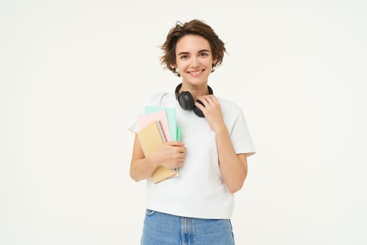 Image of stylish, modern girl student, holding workbook, documents. Woman teacher with papers standing over white background.