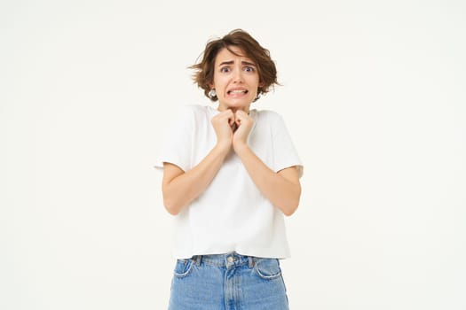 Image of woman with scared face, looks frightened, worried, trembling from fear, isolated against white background.