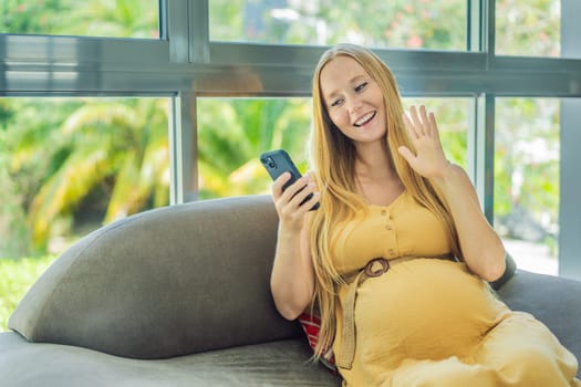 Beautiful woman holding pregnant belly and using phone, calling friends or family via video call.