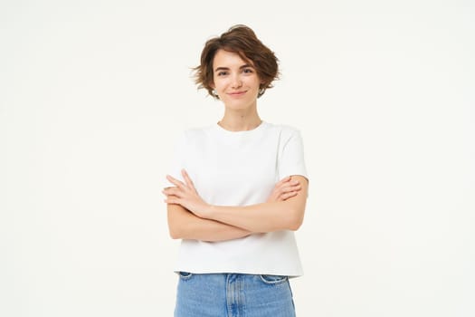 Portrait of woman standing in power pose, confident expression, cross arms on chest and smiles, stands over white background.