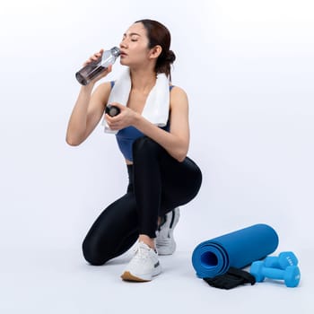 Athletic and sporty asian woman resting and drink water after intensive cardio workout training. Healthy exercising and fit body care lifestyle pursuit in studio shot isolated background. Vigorous