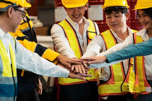Cohesive and united group of factory worker joining hands together in heavy steel industry factory exemplifying teamwork on various industrial engineering profession with team building concept.