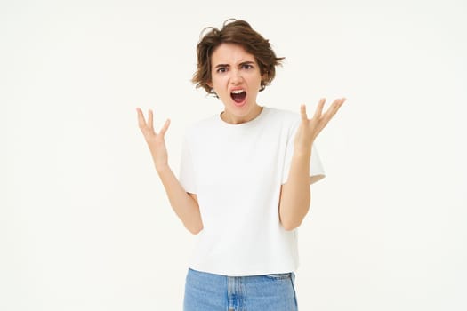 Portrait of angry woman, shaking hands and complaining, furious from frustration and disappointment, standing over white background.