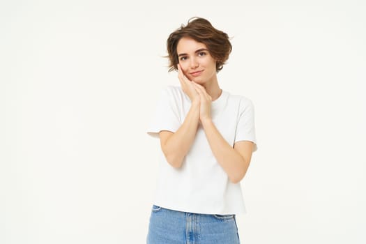 People and lifestyle. Portrait of smiling, gentle young brunette woman, gazing at camera, looking at something lovely, standing over white studio background.